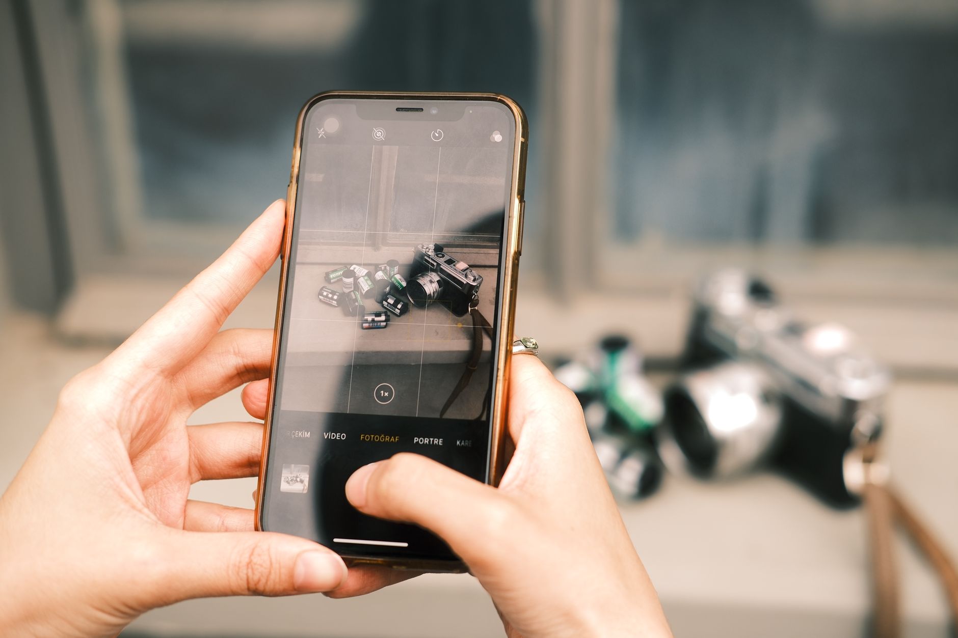 Osoba w domu fotografuje smartfonem znamię na przedramieniu, siedząc przy oknie w dziennym świetle