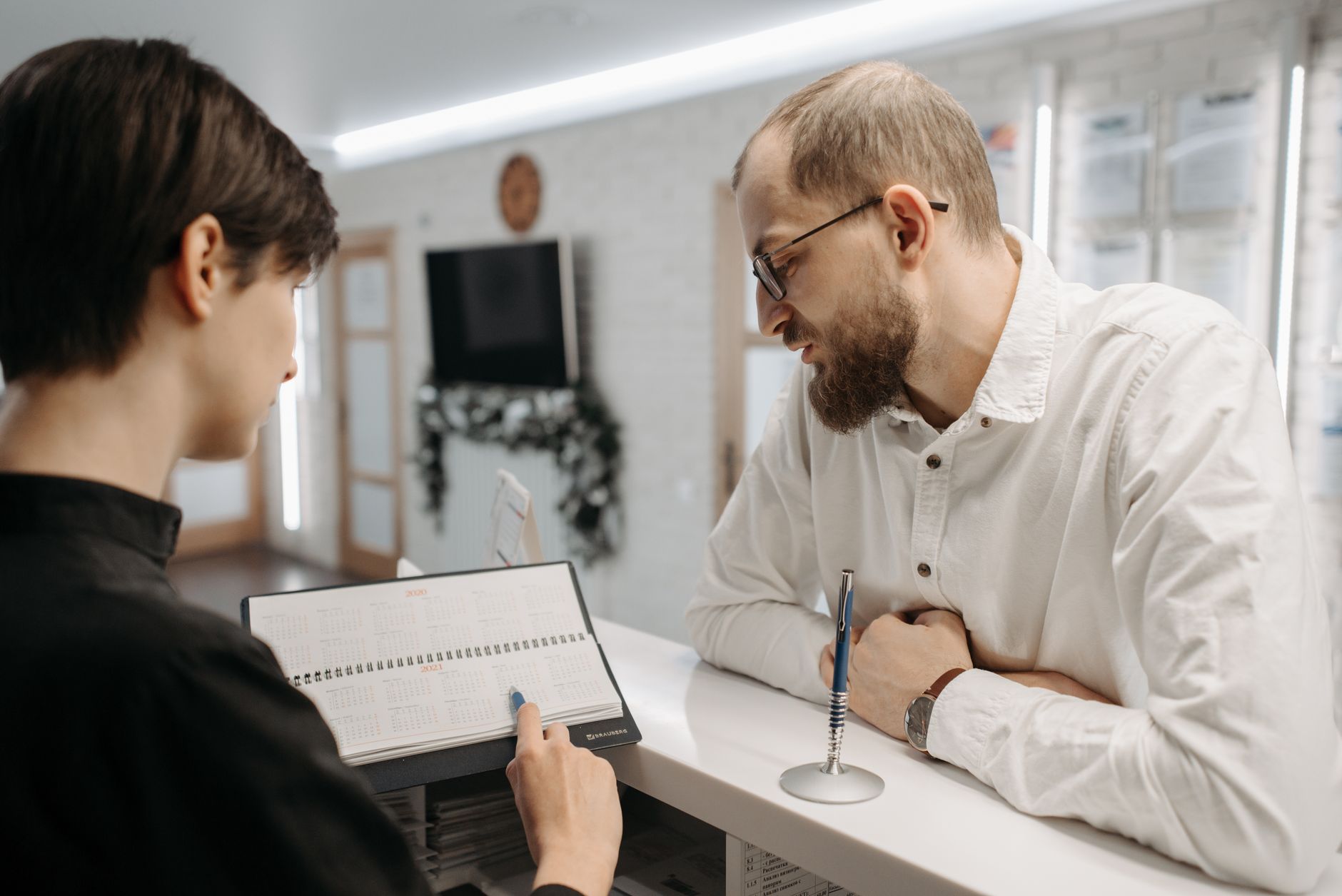 Zajęta recepcja w placówce medycznej, pracownicy pomagają pacjentom w wypełnianiu dokumentów