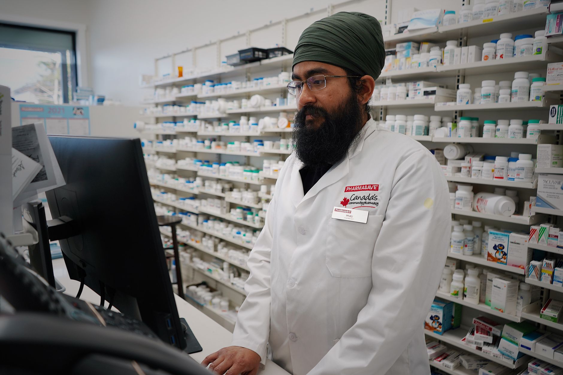 Farmaceuta przegląda tablet w aptece, otoczony półkami z lekami