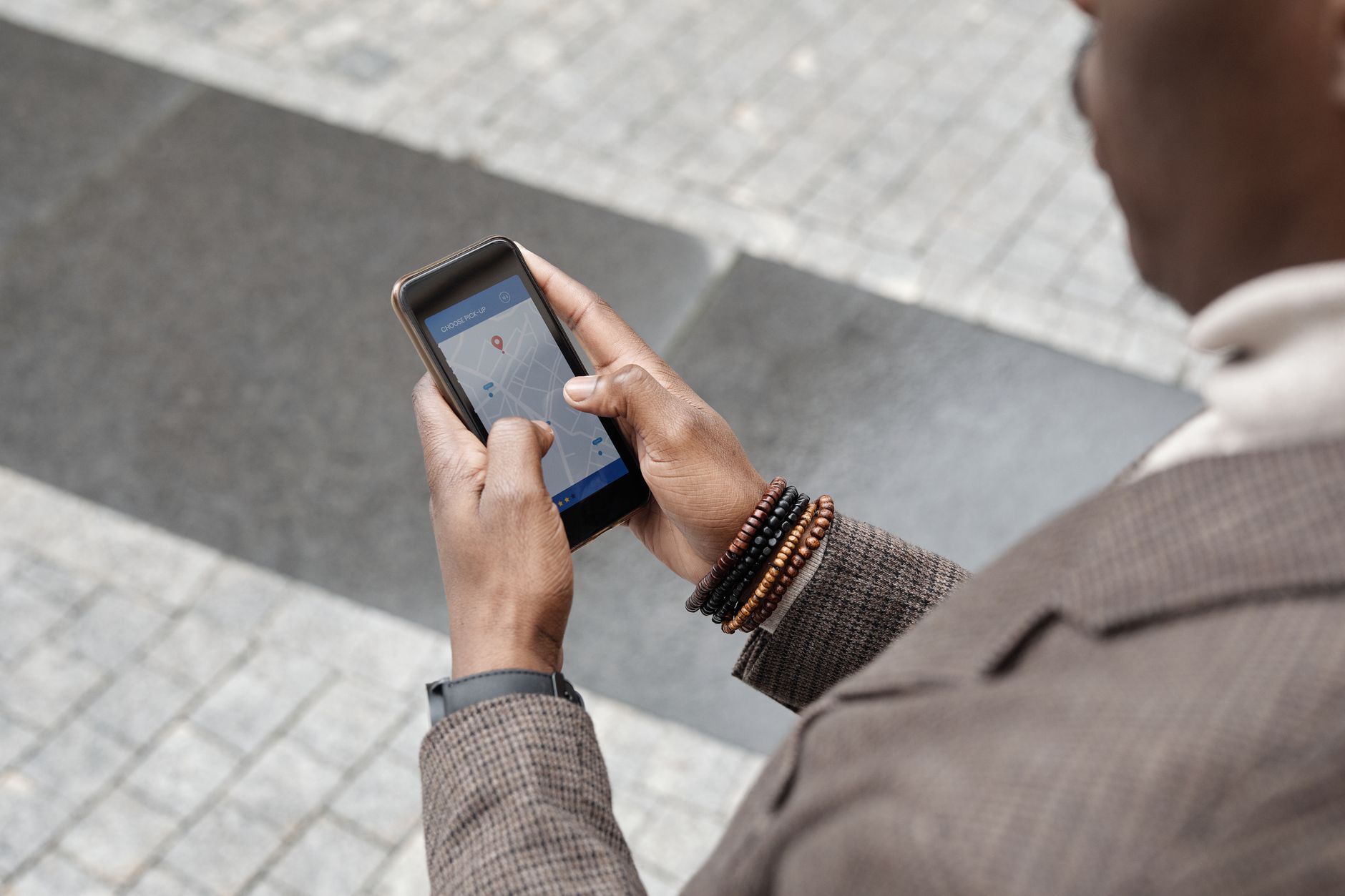 Osoba w jesiennej kurtce szuka na telefonie najbliższego punktu szczepień na ulicy miasta